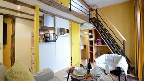 A compact living space with a kitchen, dining area, and a staircase. - E5GG Honey Mustard (París)