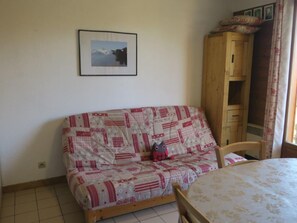 A small, cozy room with a wooden sofa and a table.