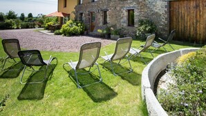 A stone building with a tiled roof, outdoor seating area with chairs, and a gravel driveway. - Large house with heated pool and spa in Manche (Savigny (Manche))