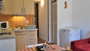 A compact kitchen with wooden cabinets, a microwave, and a small refrigerator. - Calm mountain corner studio, 4 people, parking, Risoul 1850 (Risoul)