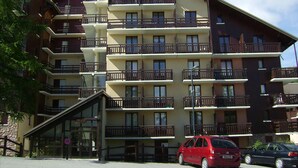 A multi-story hotel with balconies, a glass entrance, and a stone facade. - Calm mountain corner studio, 4 people, parking, Risoul 1850 (Risoul)