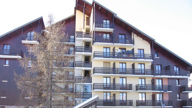 A multi-story hotel with balconies, a ski lift, and a snow-covered ground. - Calm mountain corner studio, 4 people, parking, Risoul 1850 (Risoul)
