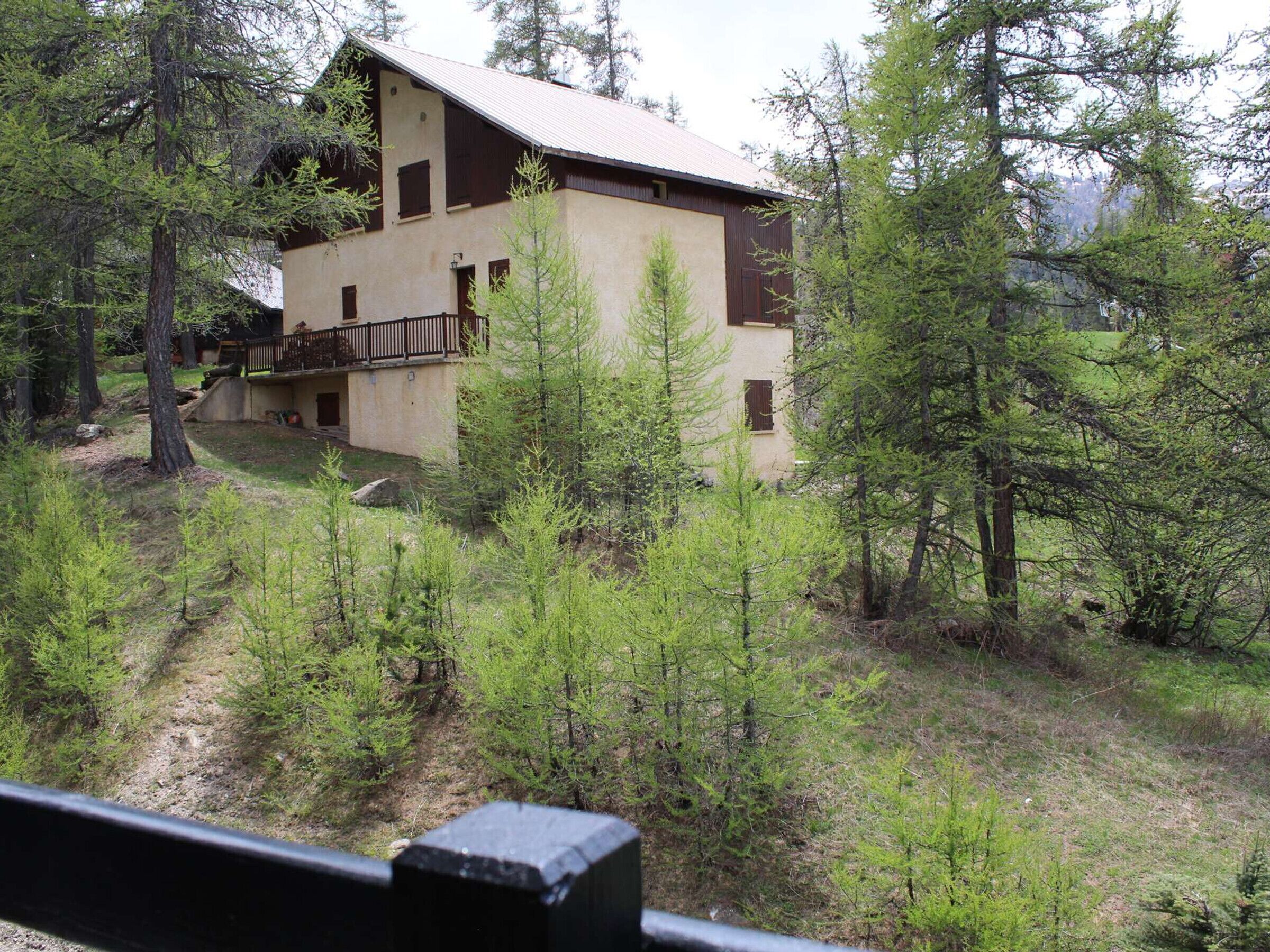 A two-story building with a balcony, surrounded by trees and a forested area.