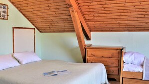A bedroom with a sloped wooden ceiling, a bed with a white mattress and pillows, a wooden nightstand with drawers, and a framed photo on the wall. - 2-room apartment for 4 - Ski-in/ski-out, summer pool (Risoul)