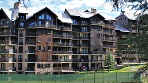 A multi-story hotel with balconies, a swimming pool, and a ski slope in the background. - 2-room apartment for 4 - Ski-in/ski-out, summer pool (Risoul)