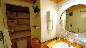 A bathroom with a toilet, a sink, a mirror, and shelves with toiletries. - B3DD Honeymoon (París)