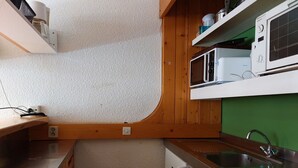 Una cocina compacta con microondas, estufa y lavabo.