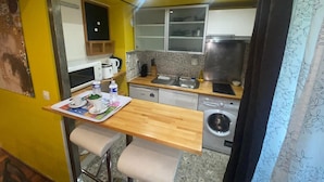 A compact kitchen with a wooden countertop, a washing machine, and a microwave.