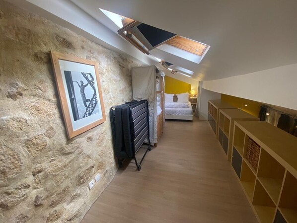 A narrow hallway with a skylight, a bed, and a wooden cabinet. - F1G Niagara (París)