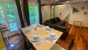 A dining area with a wooden table set for four, a black sofa, and a staircase leading to another level.