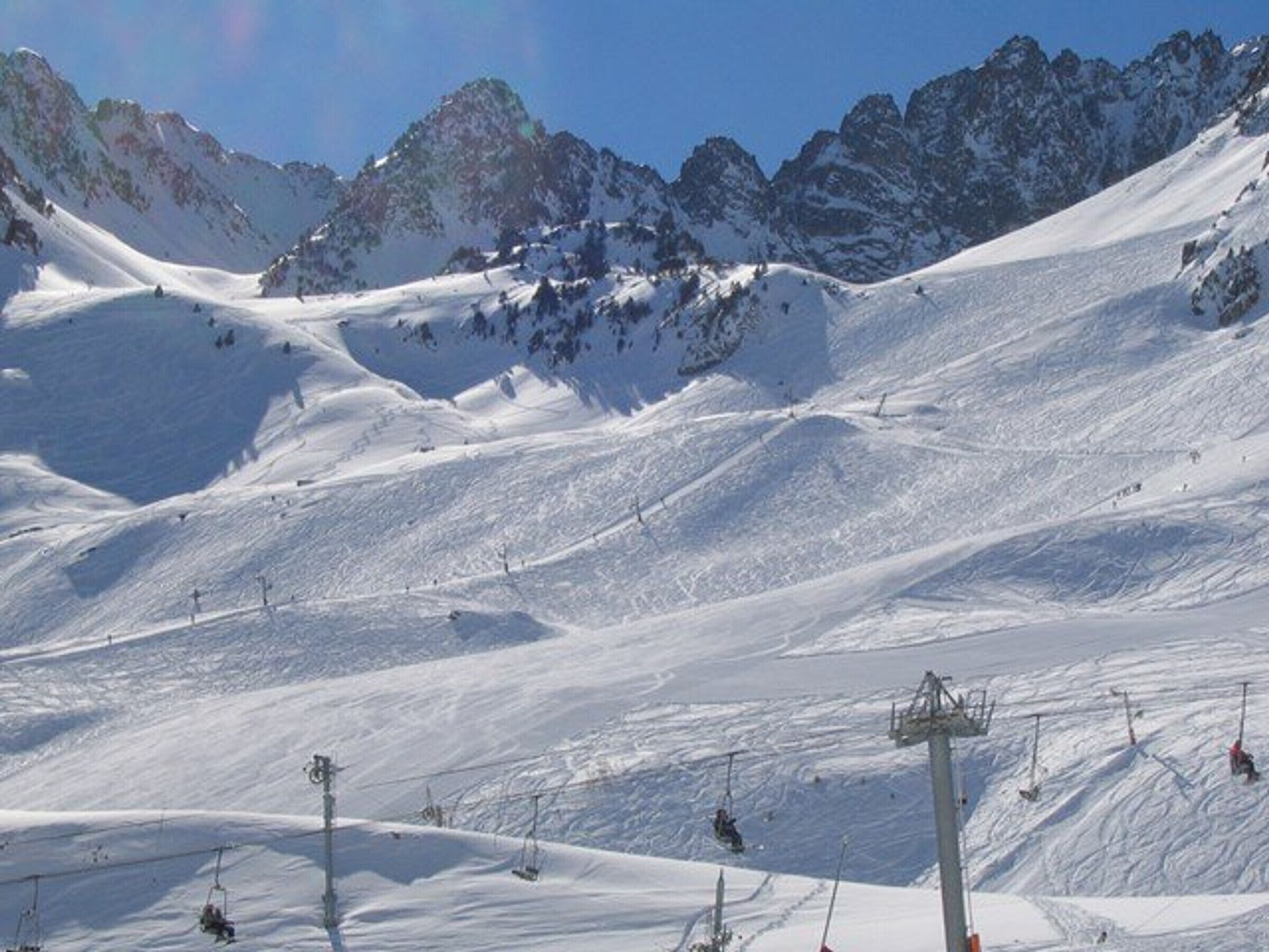 Sneklædt bjergskråning med skilifte og en klar himmel.
