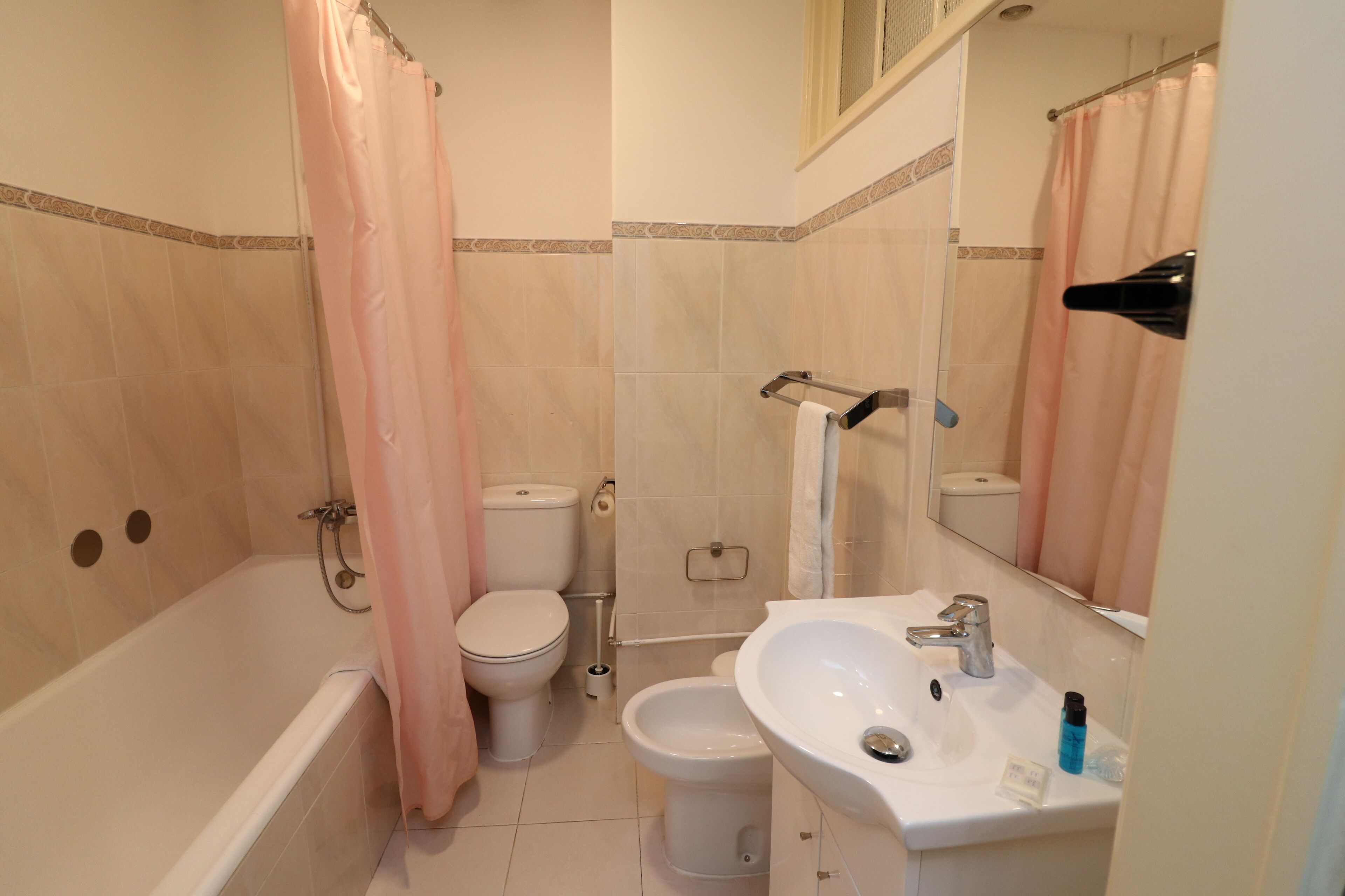 A bathroom with a bathtub, toilet, bidet, and sink.