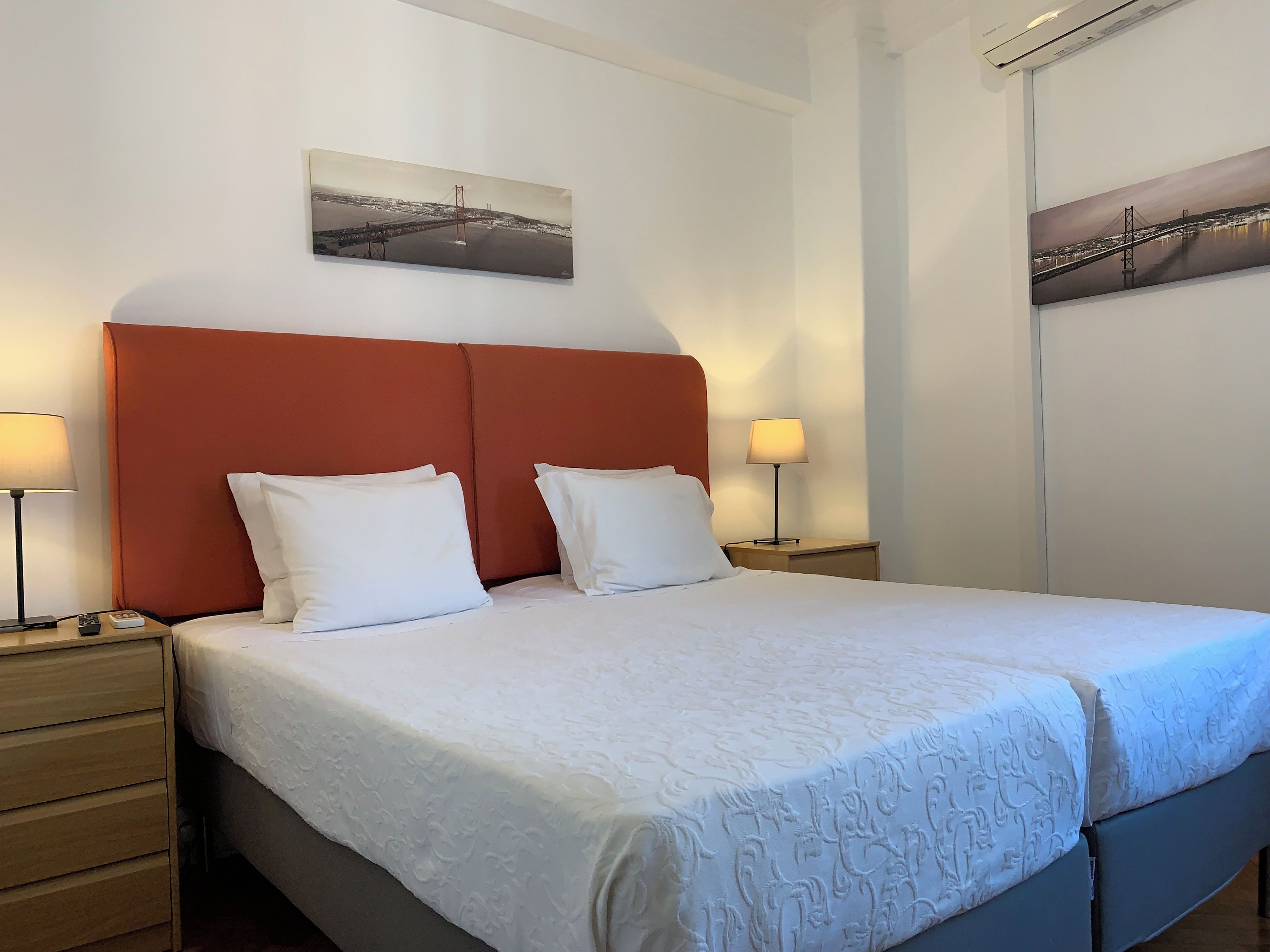 Une chambre d’hôtel avec un lit, deux lampes de chevet, une table de chevet et un tableau au mur.