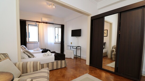 Habitación de hotel con cama, sofá, televisor y puerta corredera.
