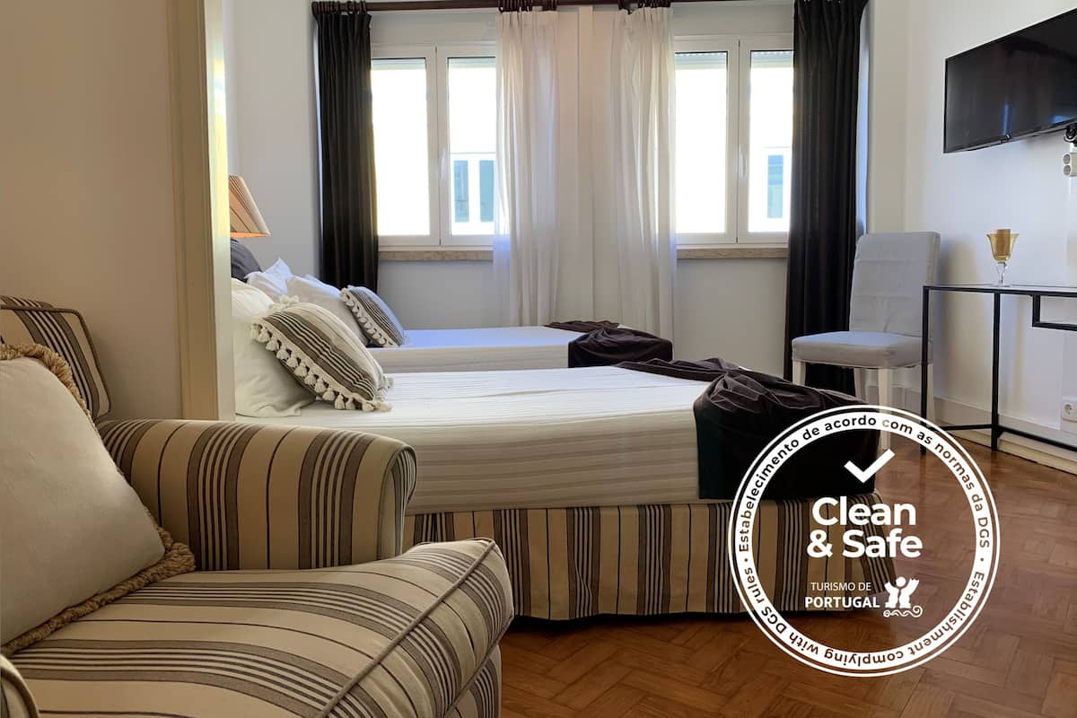 Een schone en veilige hotelkamer met een bed, een bank, een televisie en een raam met gordijnen.