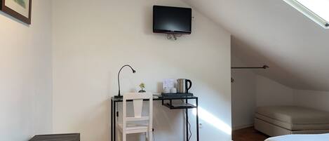 A small, tidy room with a desk, chair, and a bed.