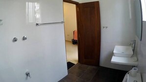 Une salle de bain avec un lavabo blanc, un miroir et un espace douche.