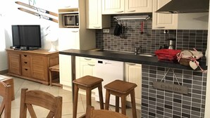 A compact kitchen with white cabinets, a black countertop, and a tiled backsplash.