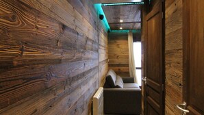 A narrow hallway with wooden walls, a radiator, and a sofa. - Sunny 3-Room Apartment for 6 with Large Terrace, Parking & Ski-In/Ski-Out Access (Huez)
