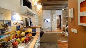 A kitchen with a coffee machine, fruit bowl, and a TV in the background. - A1G Dreaming (París)