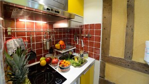 A kitchen with red and yellow tiles, stainless steel appliances, and various fruits and vegetables on the counter. - E5DD Yellow Cake (París)