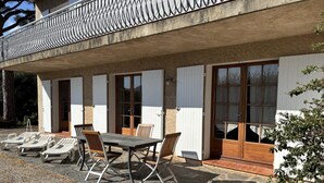 Ein Gebäude mit einer überdachten Terrasse, Sitzgelegenheiten im Freien und Blick auf die umliegende Landschaft.