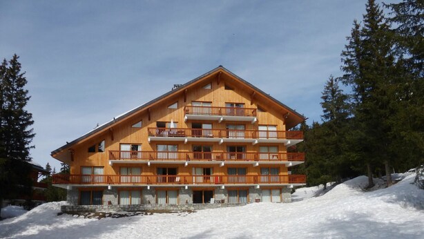 A multi-story wooden building with balconies, surrounded by snow and trees. - Cozy apartment in Méribel Altiport, 2 rooms, sleeps 6, pets allowed (Méribel)