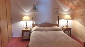 A bedroom with a wooden ceiling, a bed with a headboard, two bedside tables with lamps, and two wall-mounted pictures. - Cozy apartment in Méribel Altiport, 2 rooms, sleeps 6, pets allowed (Méribel)