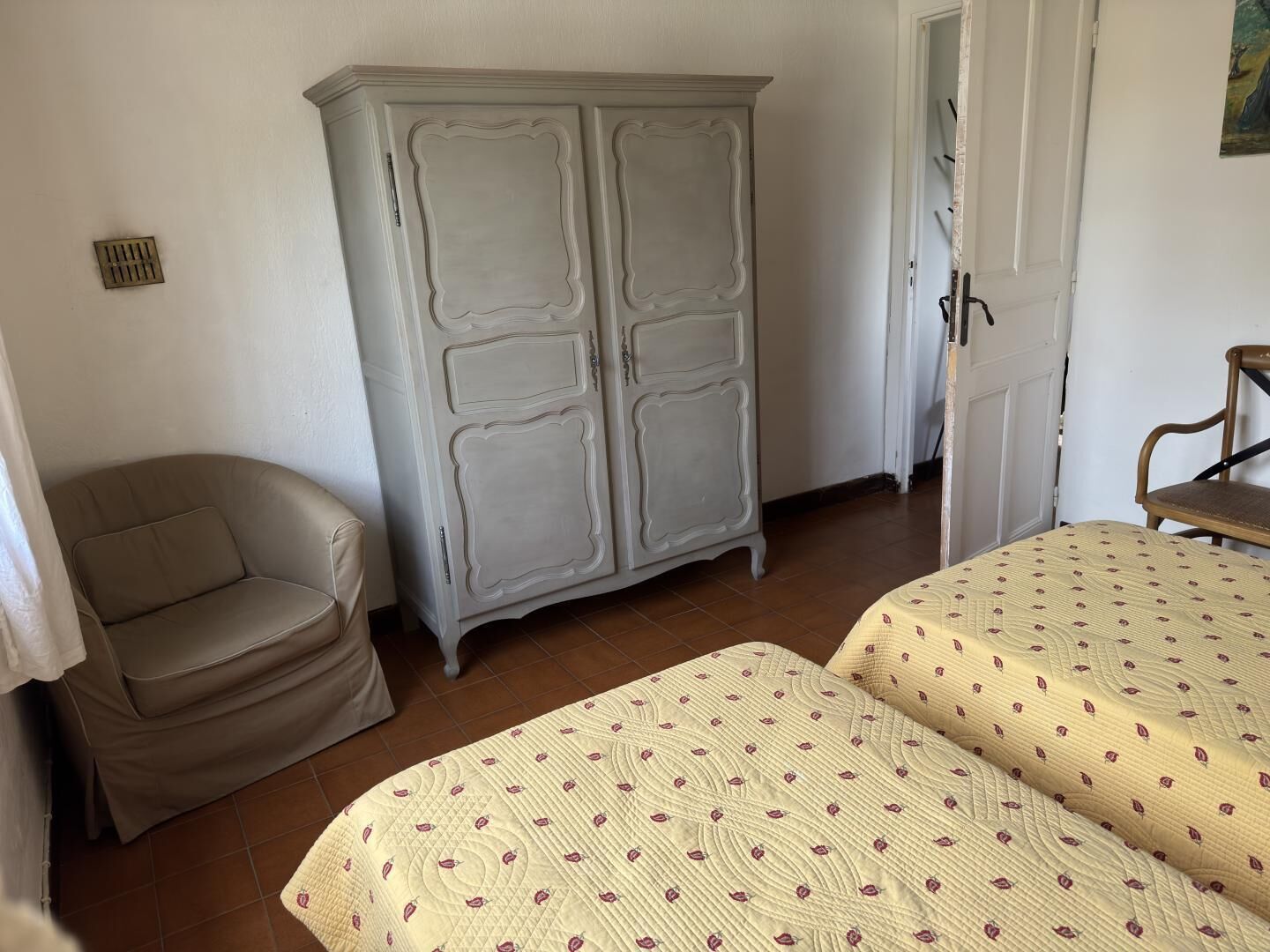 A bedroom with a bed, a chair, and a wardrobe.