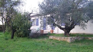 Una casa con un muro de piedra y un árbol en el jardín delantero.