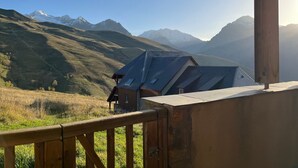Un chalet con balcón de madera con vistas a un paisaje montañoso.