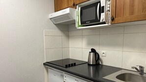 Una cocina equipada con microondas, cafetera, lavavajillas y un lavabo.
