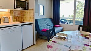 Una cocina compacta con microondas, lavavajillas y un comedor con mesa para dos.