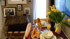 Um quarto aconchegante com uma mesa de jantar posta para o café da manhã, um espelho grande e uma parede decorada com fotografias emolduradas.