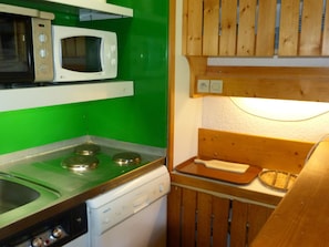 Kitchen area with a gas stove, microwave, and dishwasher, set against a green wall.