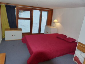 Relax in a cozy room with a large bed, a nightstand, and a window offering a serene view.
