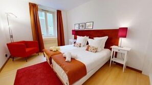 A hotel room with a large bed, red chair, bedside tables, and a window with curtains. - lacour ac 160m2 city center  4br3bth (Colmar)
