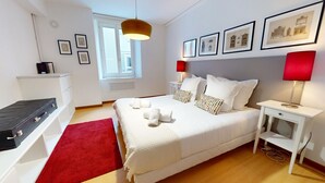 A neatly arranged bedroom with a bed, bedside tables, a desk, a red rug, and framed pictures on the wall. - lacour ac 160m2 city center  4br3bth (Colmar)