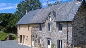 A two-story stone building with a sloped roof, multiple windows, and a gravel driveway. - Stone house in peace with pets allowed (Ouville)