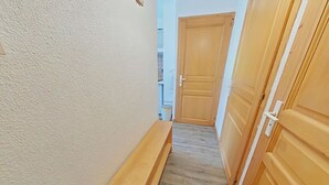 Een smalle gang met een houten bank, houten deuren en een structuurwand.