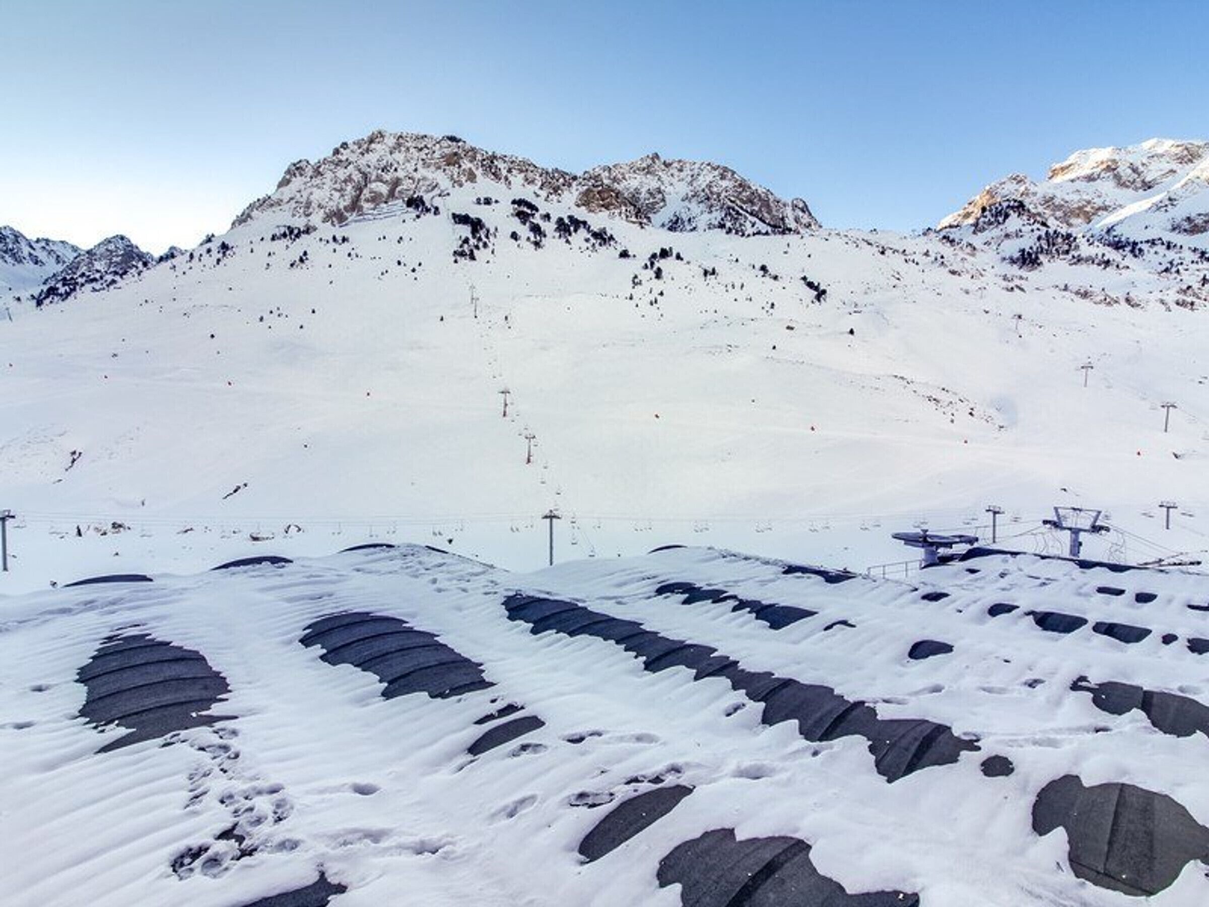 A snowy mountain landscape with ski lifts and a clear sky.