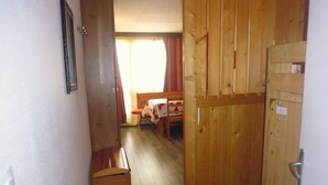 A narrow hallway with wooden doors and a bench.