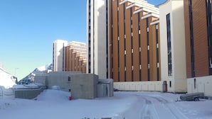 A snow-covered parking lot with a building featuring a modern design with vertical lines and a mix of brown and white colors.