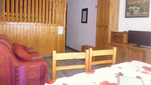 A room with a wooden bed frame, a wooden wardrobe, a television, and a framed picture on the wall.