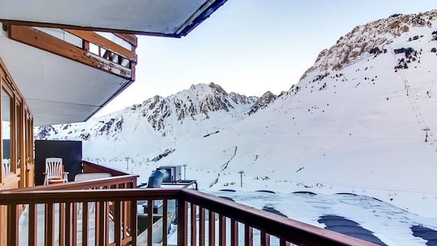 A snow-covered mountain landscape with a wooden deck and a chair.