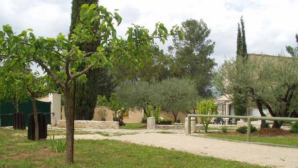 Un parque con un sendero pavimentado, árboles y un edificio al fondo.