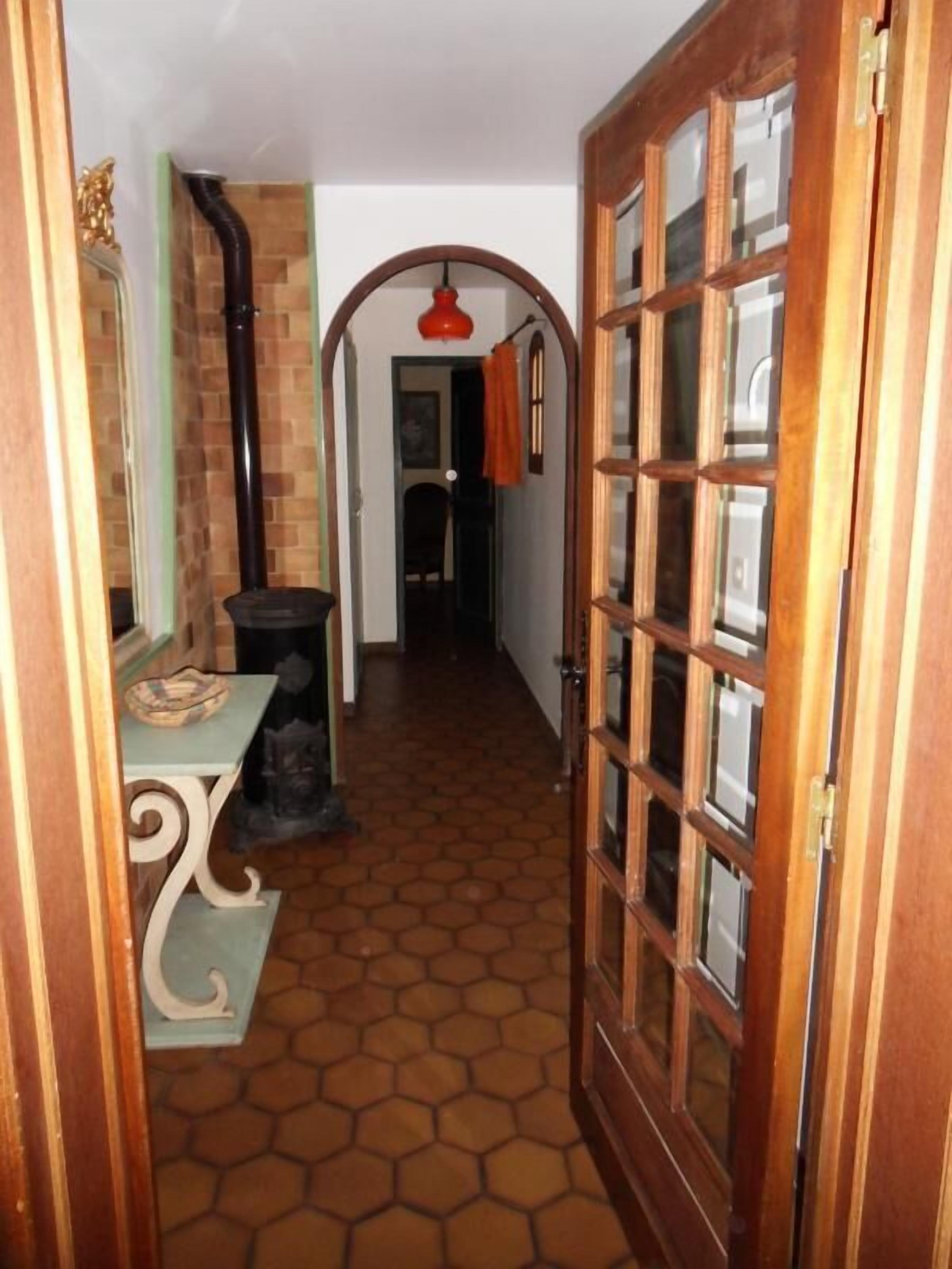 A hallway with a tiled floor, a wooden door with glass panels, and a brick wall.