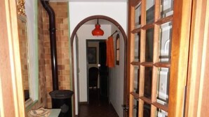 Un pasillo con suelo de baldosas, una puerta de madera con paneles de vidrio y una pared de ladrillo.
