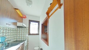 A compact kitchen with wooden cabinets, a patterned backsplash, a window with a view, and a radiator. - Studio Cabin 4 Sleeps, Ski-In/Ski-Out, South-Facing Balcony, Le Grand-Bornand (Le Grand-Bornand)