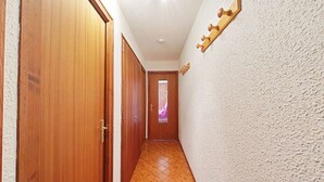 A hallway with wooden doors, a textured wall, and a patterned floor. - Studio Cabin 4 Sleeps, Ski-In/Ski-Out, South-Facing Balcony, Le Grand-Bornand (Le Grand-Bornand)